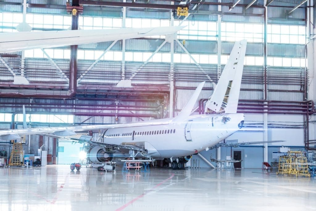 Passenger aircraft under maintenance. Checking mechanical systems for flight operations. White jet plane in the hangar