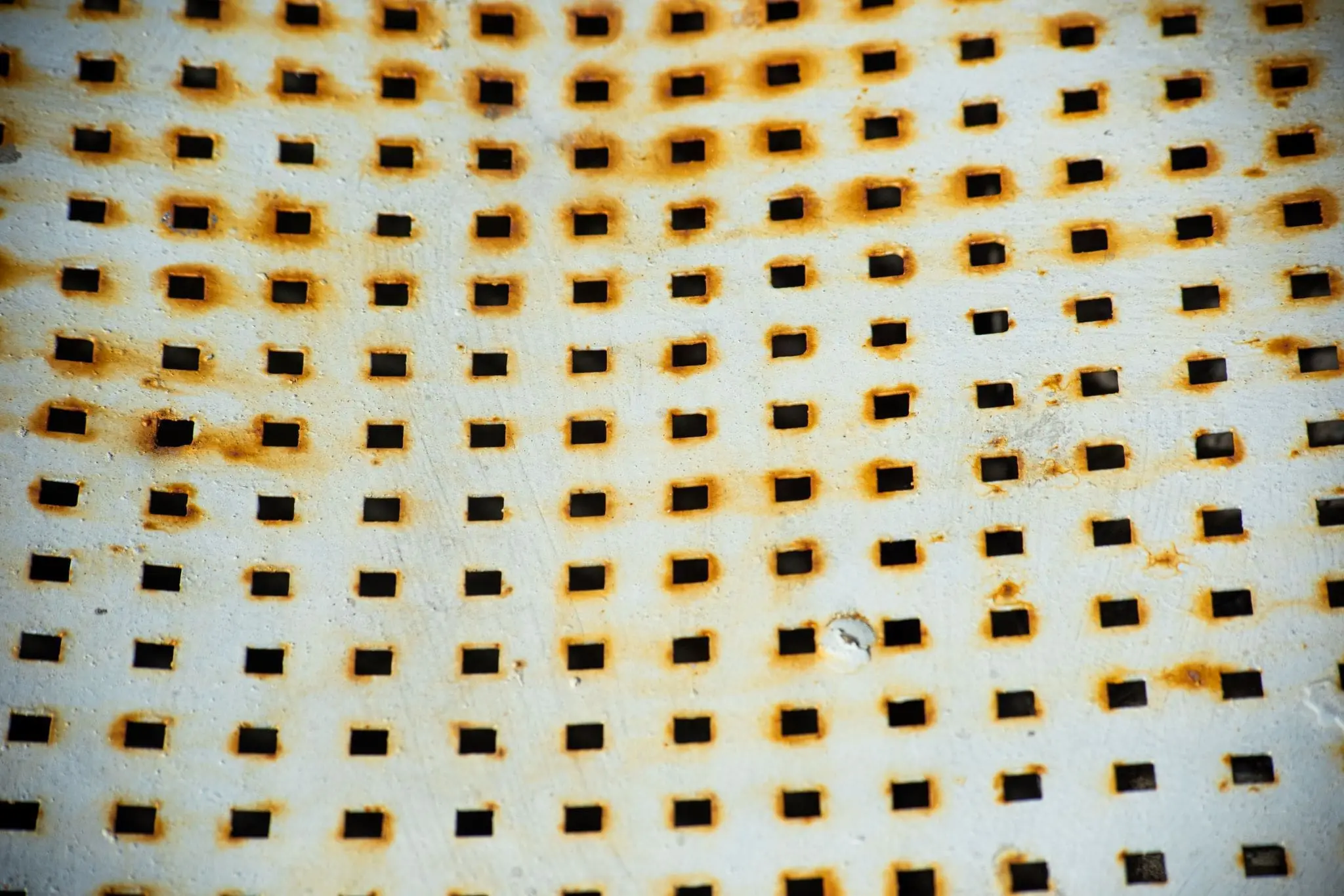 coated metal plate with square perforations and pitting corrosion