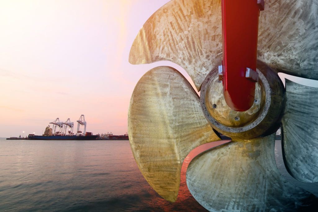 Detail of black stern and ship propeller with shipyard in the distance