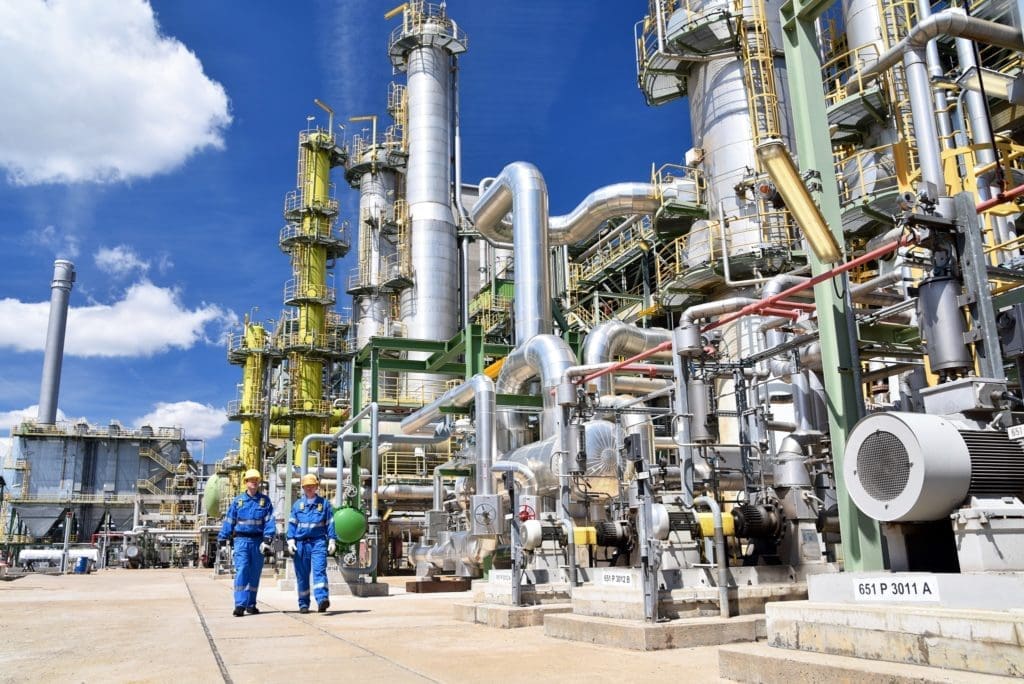 chemical industry plant - workers in work clothes in a refinery with pipes and machinery, cold spray technology can assist this industry