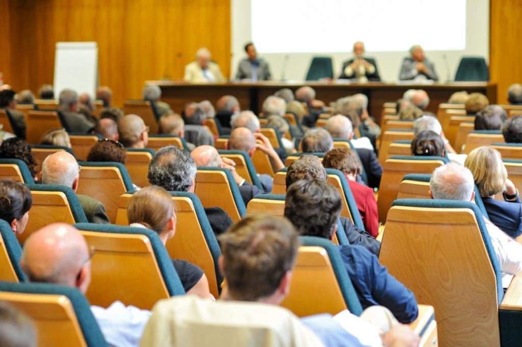 a group of scientists in a symposium, similar to meetings where researchers explained cold spray technology 